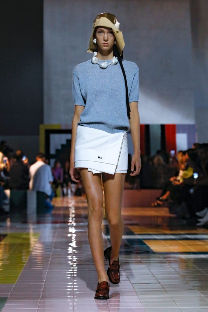 runaway model on cat walk wearing a white skirt and blue jumper with beret