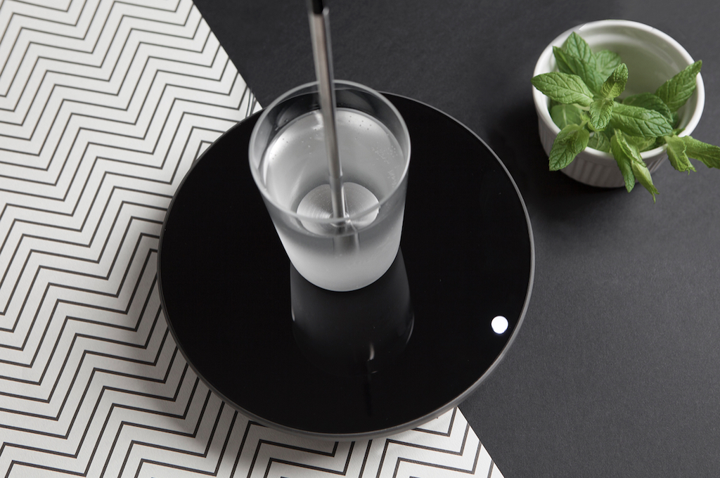 A glass cup with rod placed on a black plate in the kitchen