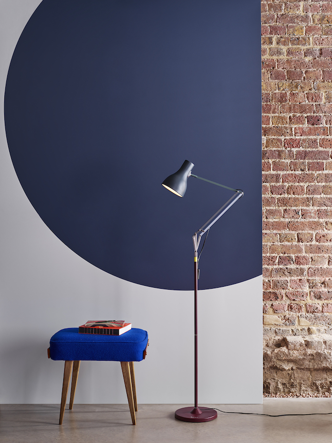 Blue and burgundy Paul Smith floor lamp in front of a brick and painted wall.